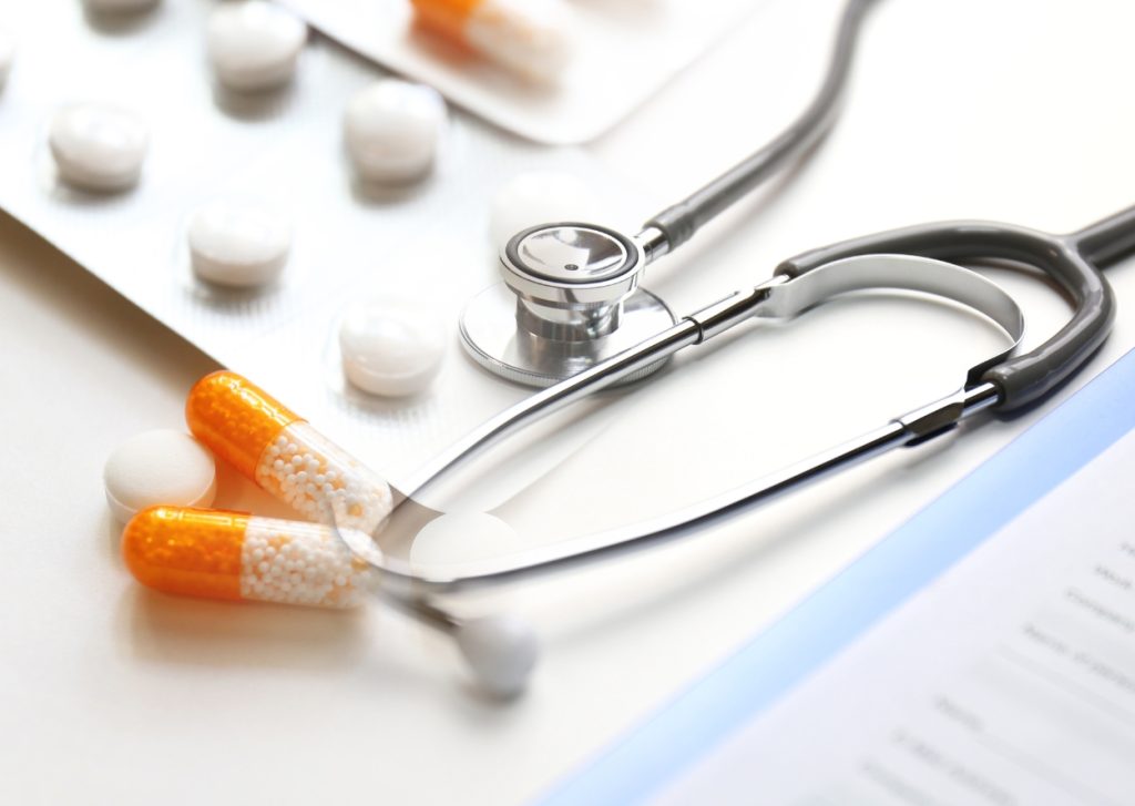 IMP. Area of expertise. Pills on the white table. Stethoscope next to some white paper.