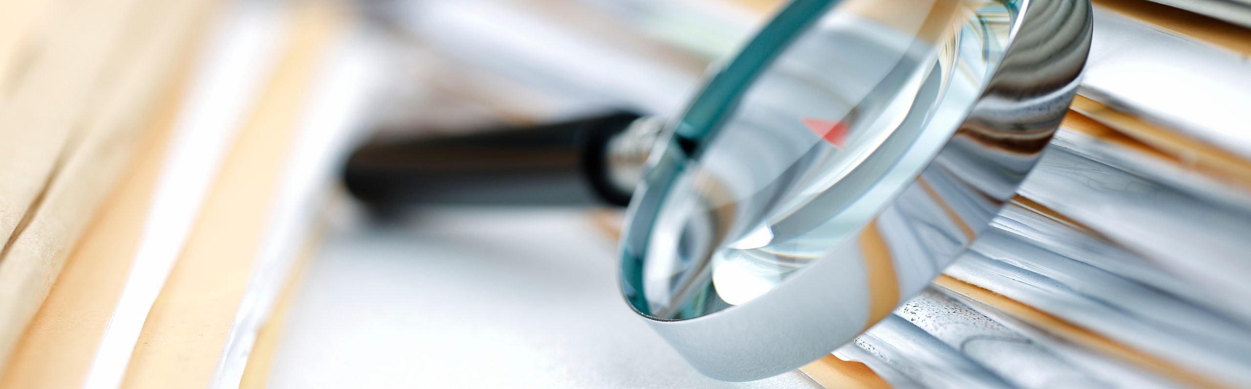 Magnifying glass over documents, symbolizing GxP audits conducted by SciencePharma. The image represents advanced GxP audit services, including GMP, GLP, GCP, and pharmacovigilance (PhV) system assessments. SciencePharma offers GMP audits for laboratories, medicinal product manufacturing sites, warehouses, and packaging material facilities. It also specializes in GCP audits for clinical trials, including SOP verification, vendor qualification, and clinical trial audits. Additionally, the company performs GLP audits for nonclinical studies and clinical trial analyses, as well as GMP/GDP compliance audits and pharmacovigilance system audits.