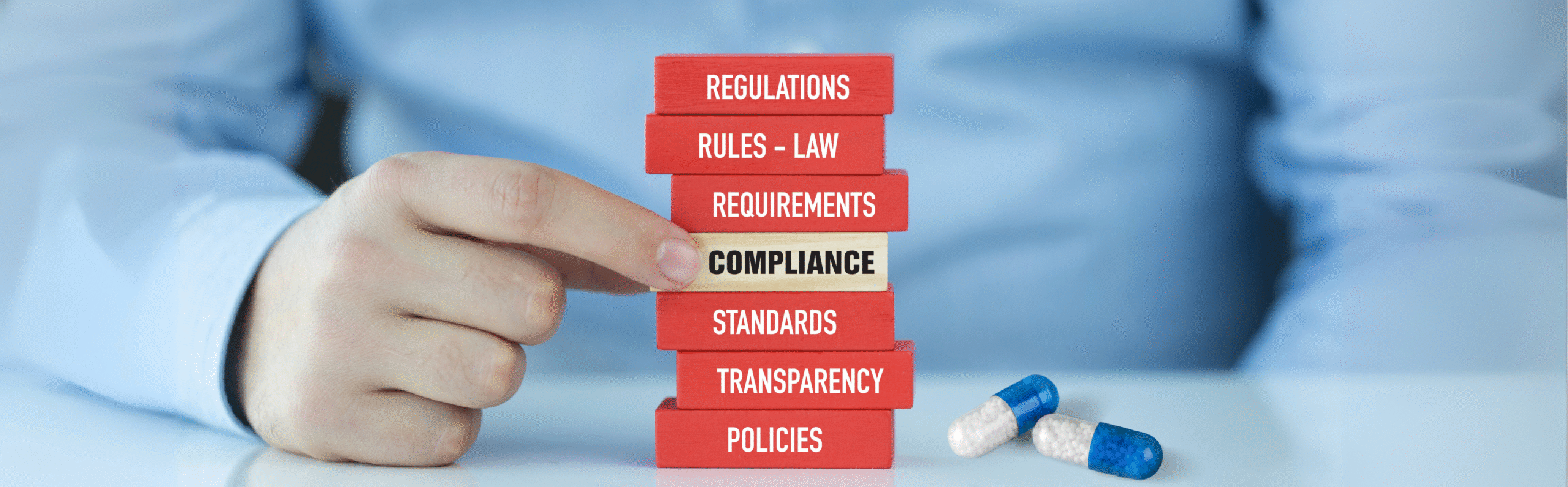 Hand stacking wooden blocks labeled “Compliance”, “Regulations”, “Rules”, “Law”, and “Requirements”, symbolizing the structured and expert approach to xEVMPD data submission and regulatory alignment under Article 57, EMA, GVP, and ISO IDMP standards. The image represents pharmacovigilance obligations, EMA reporting, medicinal product lifecycle management, and regulatory compliance support for MAHs in the EU/EEA.